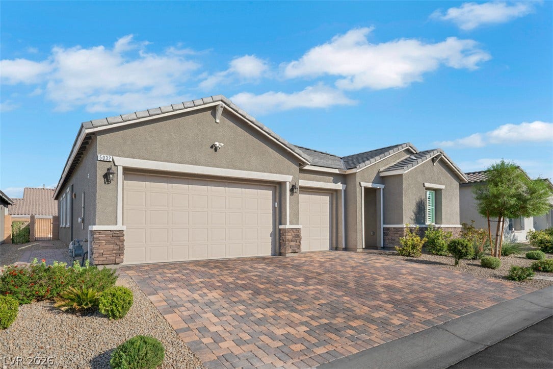 An inviting stone-accented facade stands out alongside a sprawling paver driveway.