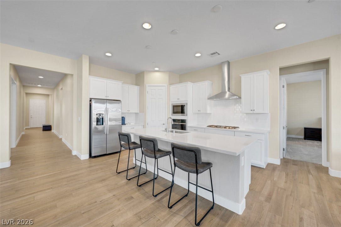 Gleaming hardwood floors and a spacious stone-topped island define this airy open-concept kitchen.