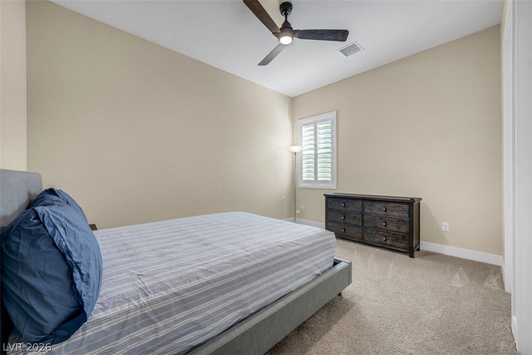 High ceilings and neutral finishes define this serene guest room with plush carpeting.
