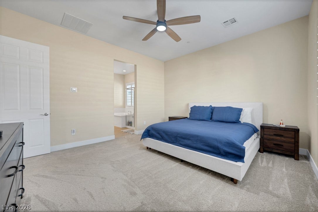 A spacious bedroom features wall-to-wall carpeting and connects directly to a private bathroom.