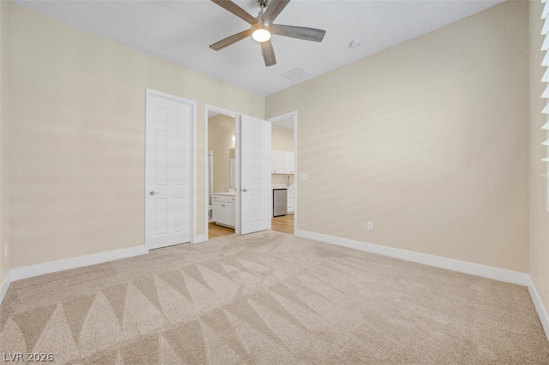 A spacious bedroom features plush carpeting, high ceilings, and direct access to an en-suite bath.