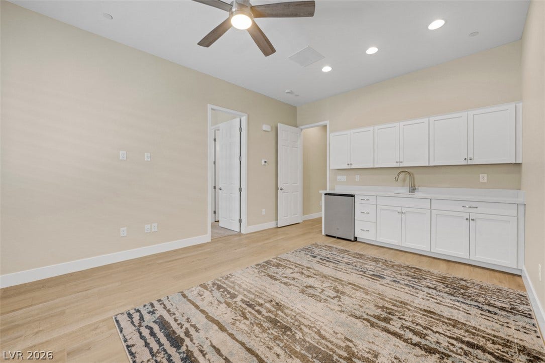 Smooth wood floors anchor this versatile bonus room with a convenient wet bar setup.