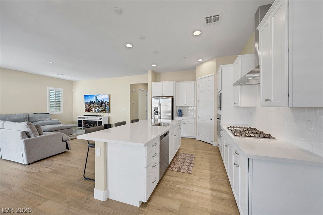 An open-concept kitchen seamlessly integrates with the living area over clean wood floors.