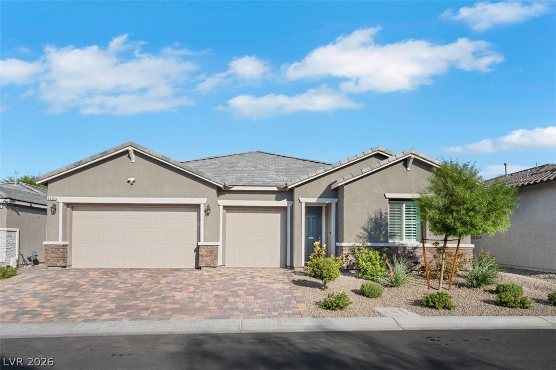 An inviting stone-paved driveway leads to a modern single-story residence with clean stucco finishes.