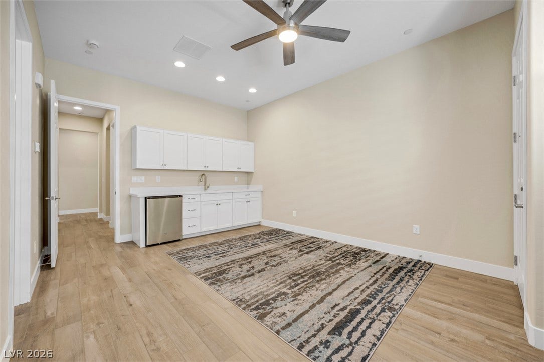 Recessed lighting and warm wood flooring frame a versatile space complete with a built-in wet bar.