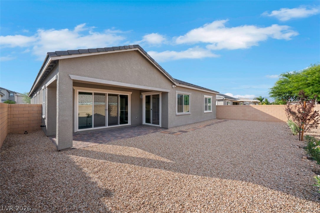 Sliding glass doors open to a covered patio and low-maintenance gravel yard.