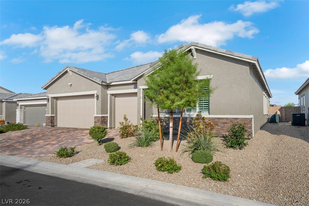 Desert landscaping and a paved driveway complement this modern single-story residence with a multi-car garage.