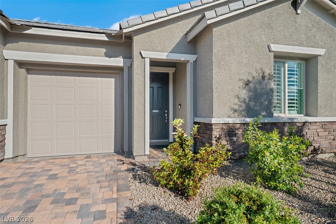 Textured stucco and stone veneer accents complement the paved driveway leading to the entrance.