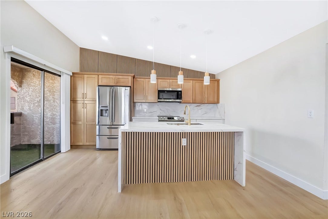 Slanted high ceilings and a slatted wood island highlight this modern open kitchen.