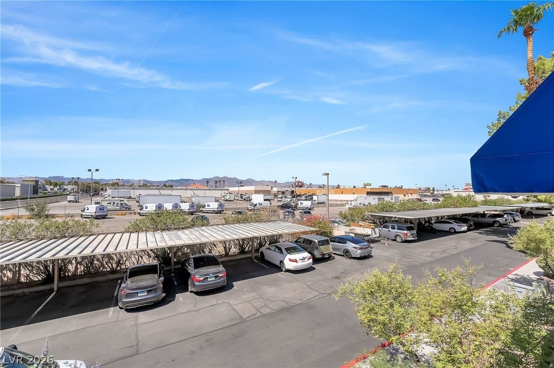 Distant mountains frame the horizon beyond the covered parking areas under a bright blue sky.