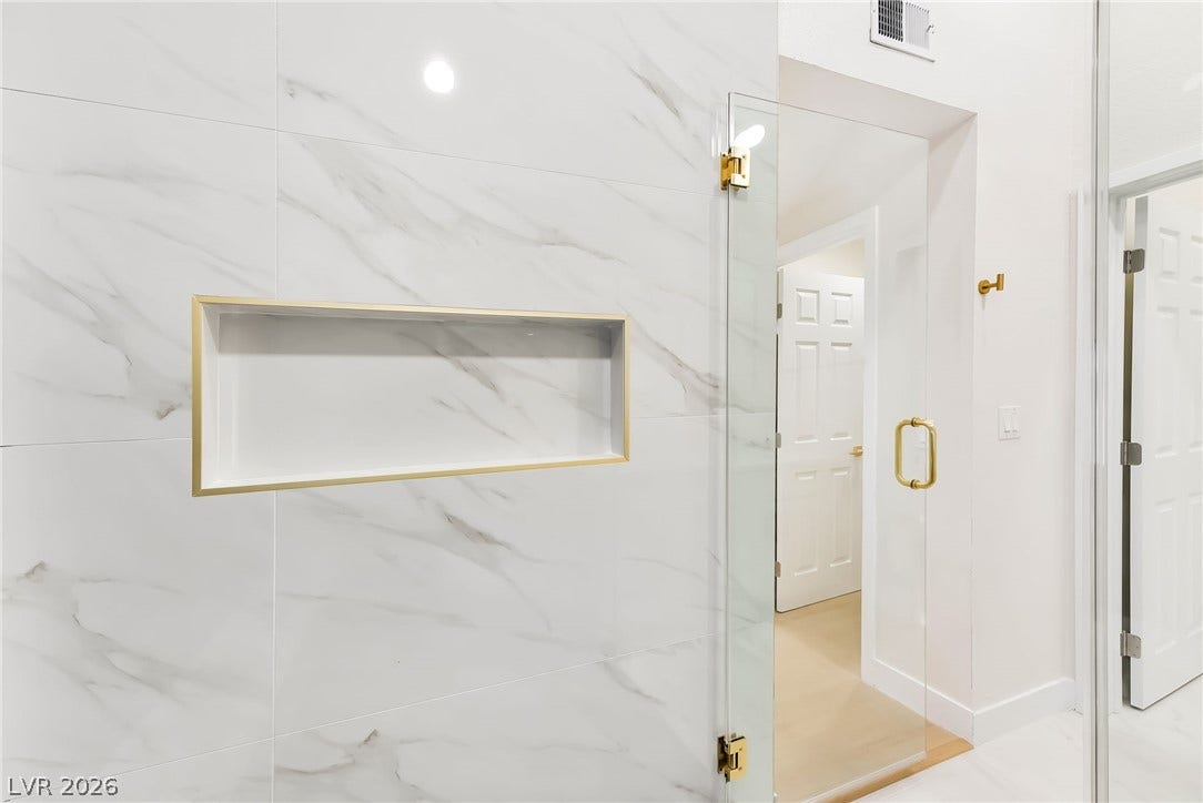 Elegant marble-patterned tile pairs with gold-toned fixtures in this modern walk-in shower design.