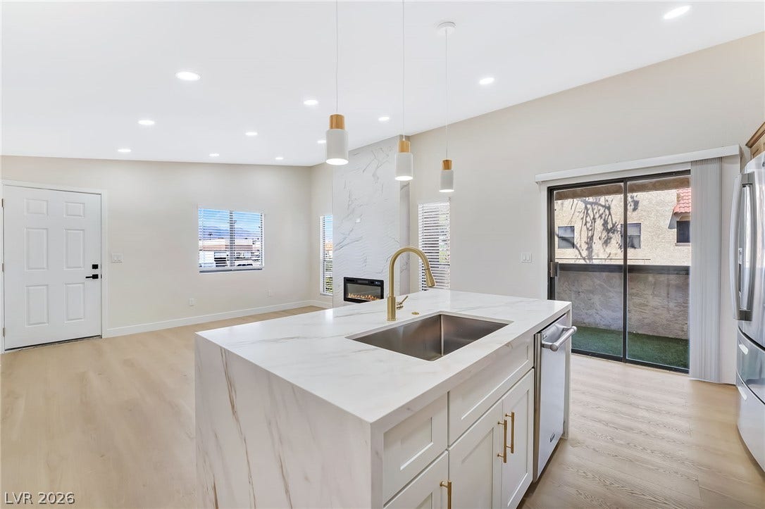 Gleaming stone countertops and wood flooring anchor this airy, open-concept living space.