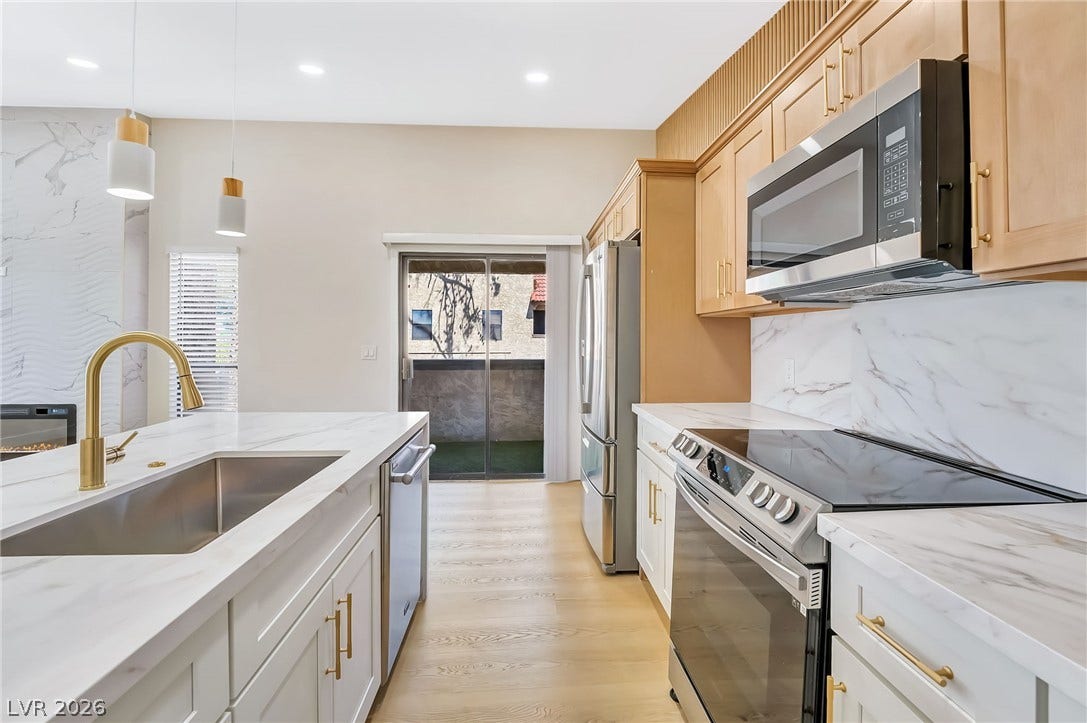 Elegant stone countertops and modern cabinetry frame a bright, open culinary space with balcony access.
