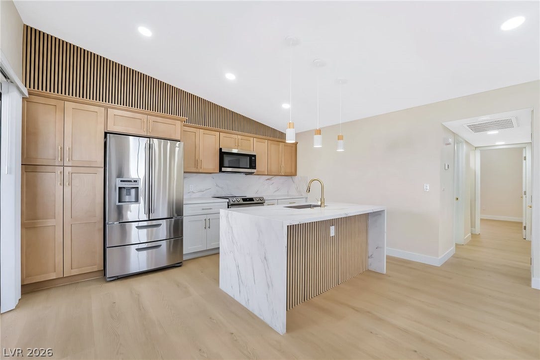 Elegant wood-paneled walls and a stone island define this modern culinary workspace.
