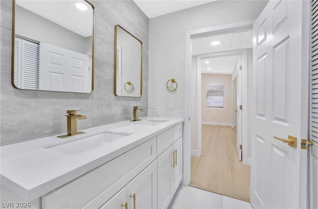 A contemporary double vanity highlights this bathroom with clean lines and warm gold accents.