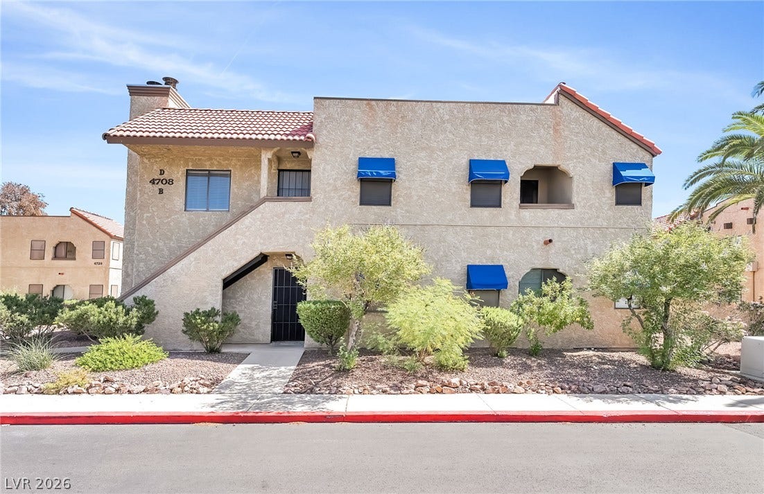 Spanish tile accents and distinctive blue awnings elevate this multi-level stucco exterior.