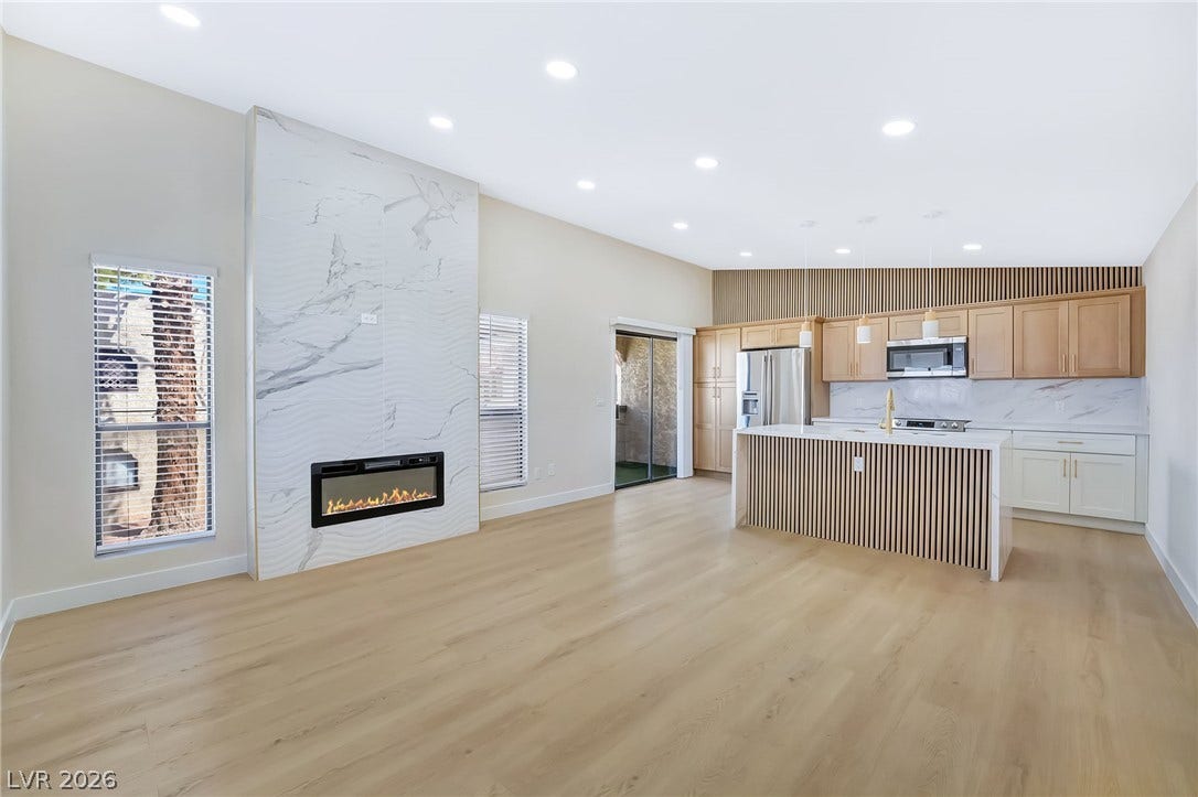 A modern fireplace clad in marble-style tile commands attention in this airy open-concept living space.
