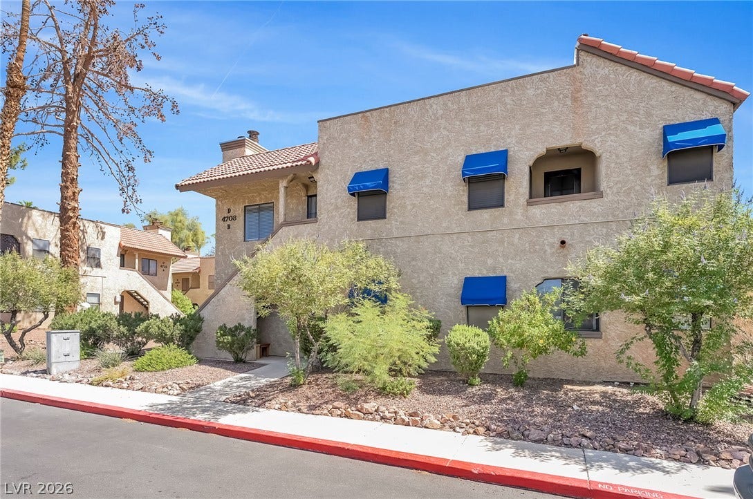 Spanish tile rooflines and bright blue awnings define this multi-level stucco exterior.