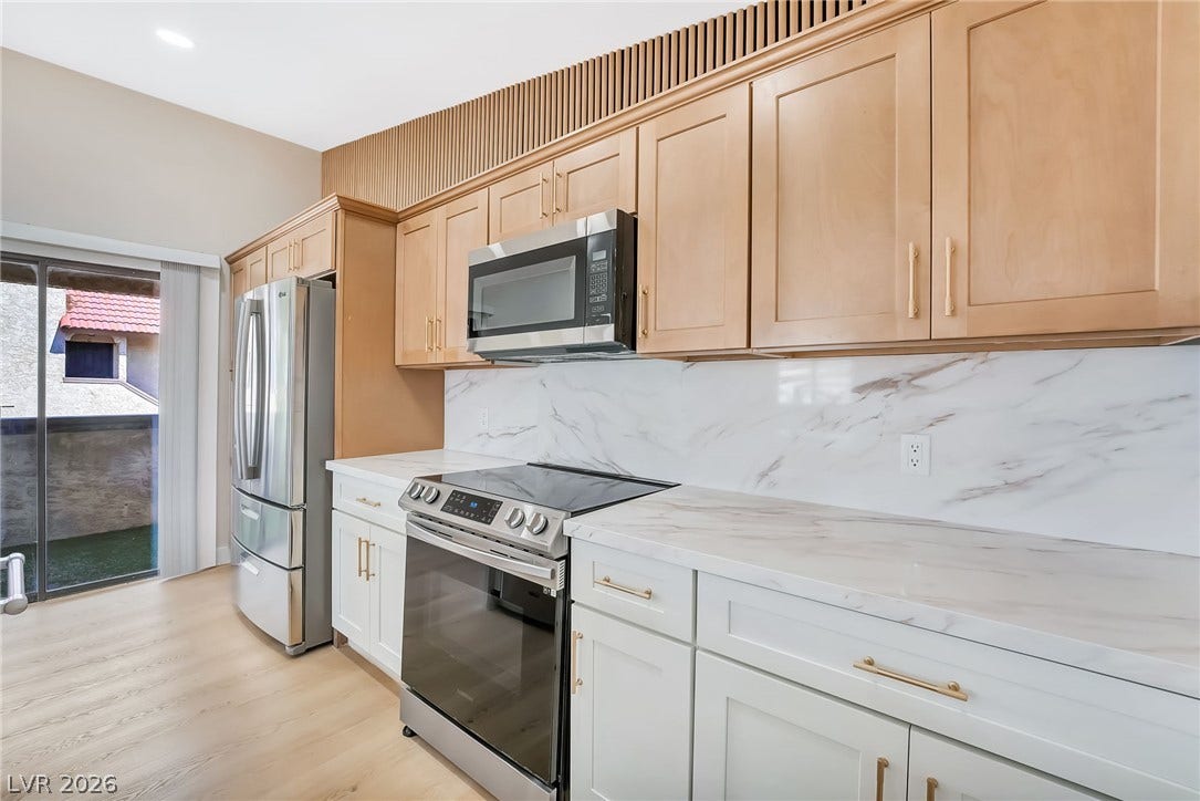 Gleaming stone countertops and modern built-ins elevate this light-filled kitchen space.