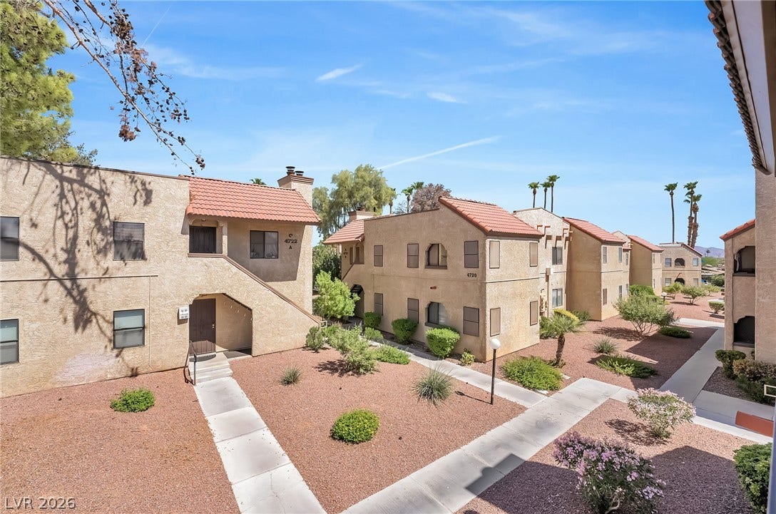 Paved walkways wind through landscaped grounds showcasing Mediterranean-inspired architectural design elements.