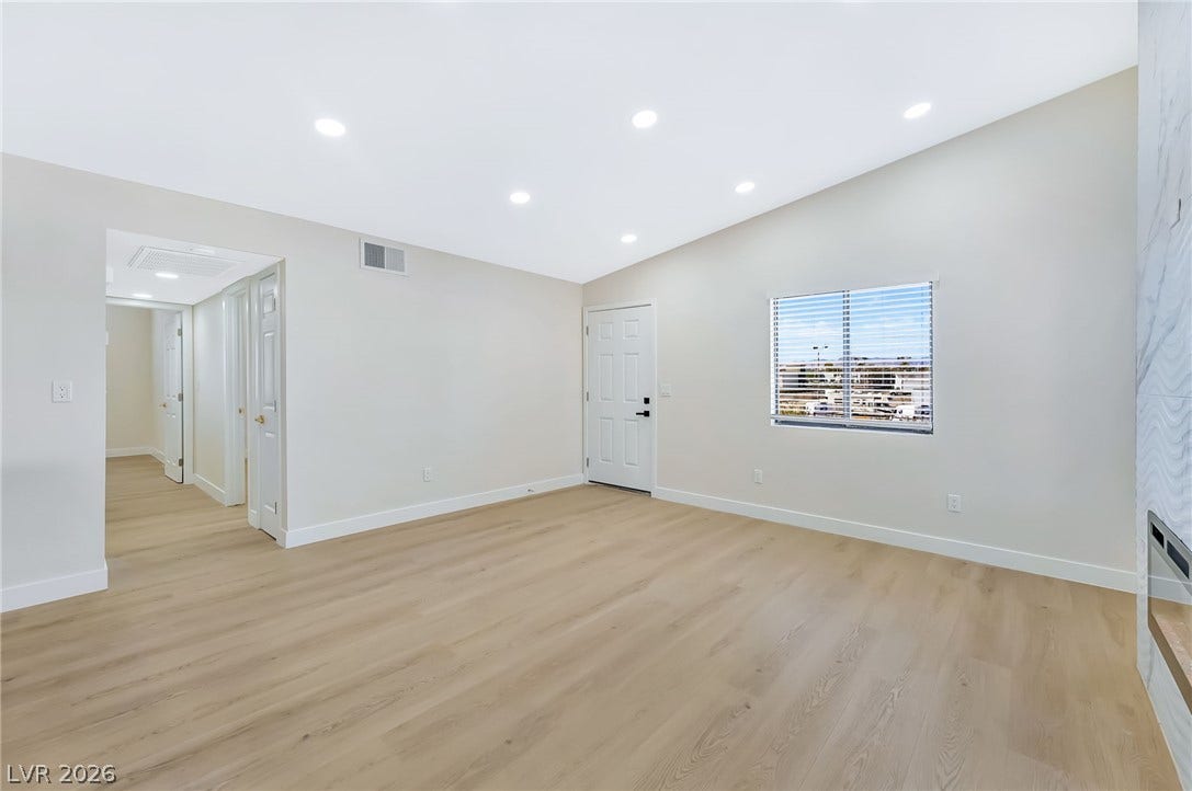 Recessed lighting and warm wood flooring enhance this open, high-ceilinged living space.