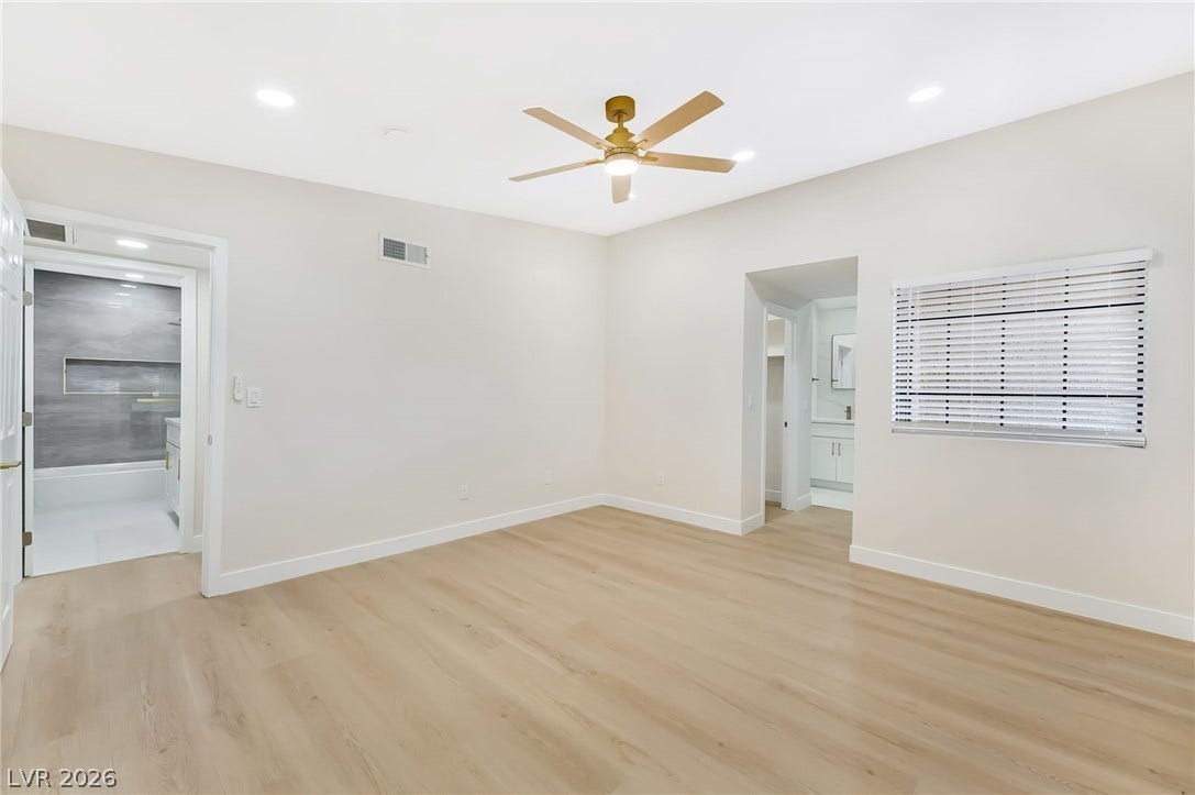 Smooth wood floors and recessed lighting anchor this serene bedroom suite with attached bath.