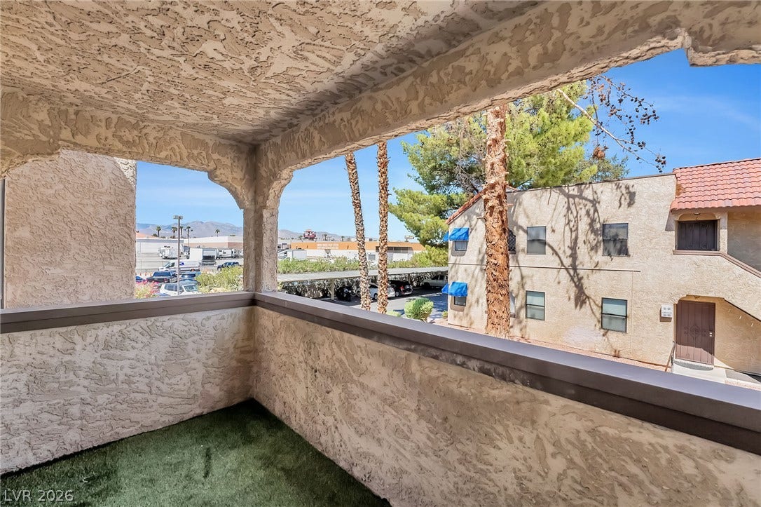 An arched covered balcony looks out over the surrounding neighborhood under sunny skies.