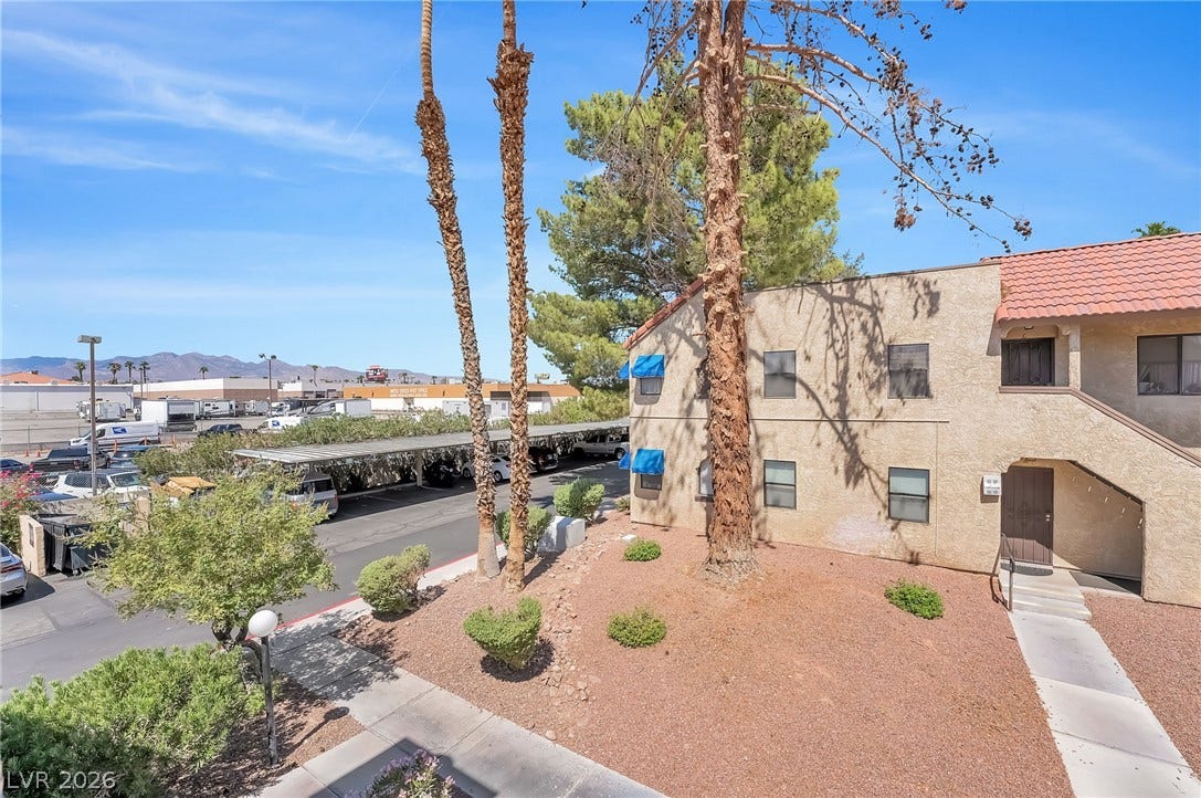 Mature trees and landscaping frame the stucco exterior of this multi-level residential building.