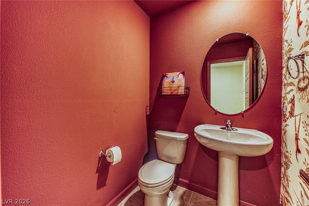 264 Banished Avenue, #2, North Las Vegas, NV 89031 A well-appointed powder room features a pedestal sink and an elegant round mirror.