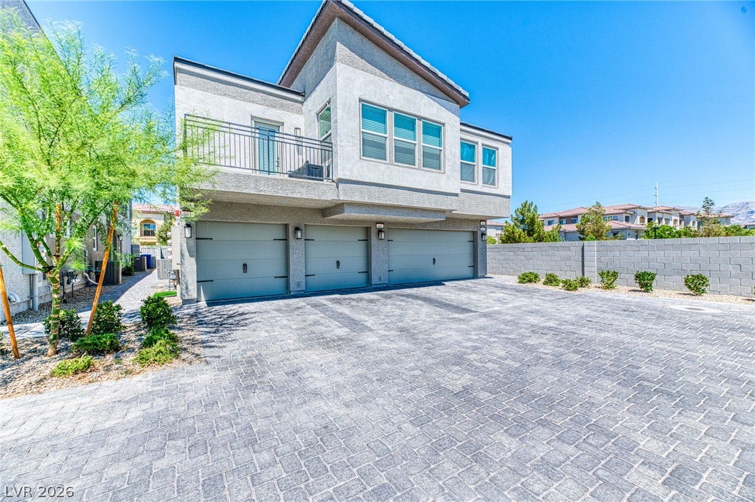 264 Banished Avenue, #2, North Las Vegas, NV 89031 A contemporary exterior features an elevated balcony above three garage doors, all set against a clear sky.