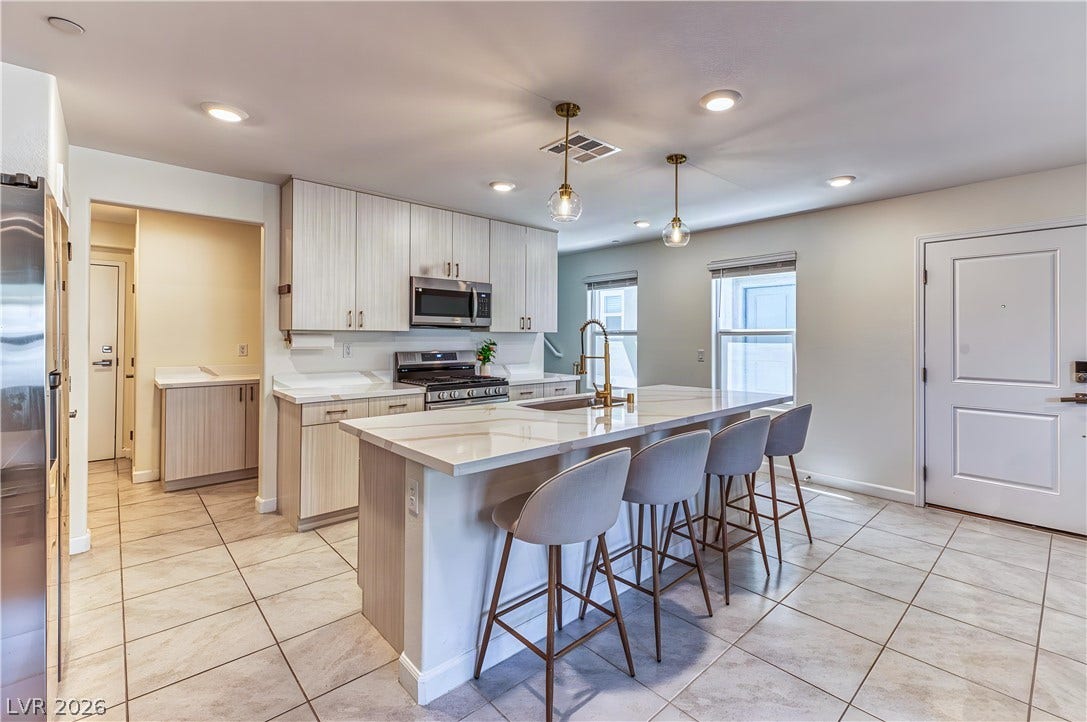 264 Banished Avenue, #2, North Las Vegas, NV 89031 An open kitchen offers sleek stone countertops alongside a central island and tile flooring.