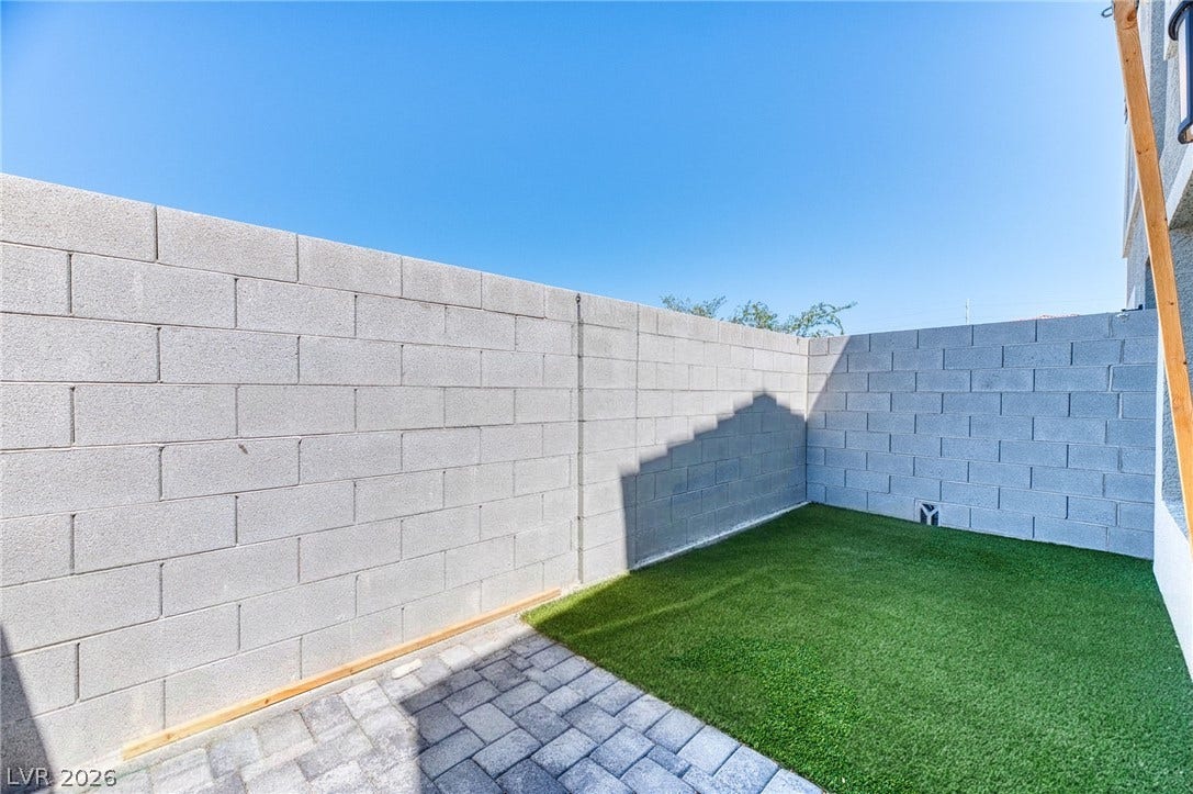 264 Banished Avenue, #2, North Las Vegas, NV 89031 An enclosed backyard features brick pavers alongside a level lawn patch beneath clear blue skies.