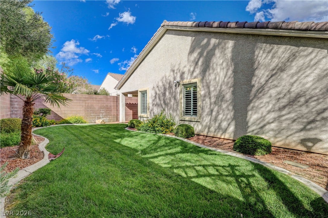 Manicured green lawns and stucco walls define this private yard under clear desert skies.