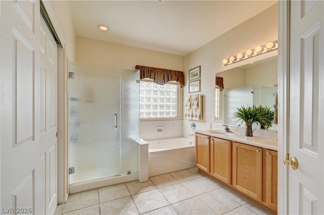 A spacious layout highlights the separate soaking tub and tile flooring in this primary bath.