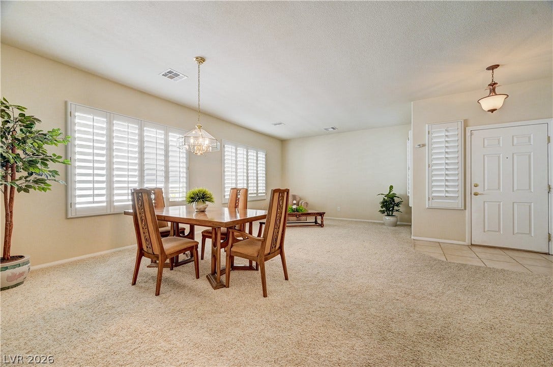 An open dining area flows seamlessly into the main living space over soft neutral carpeting.