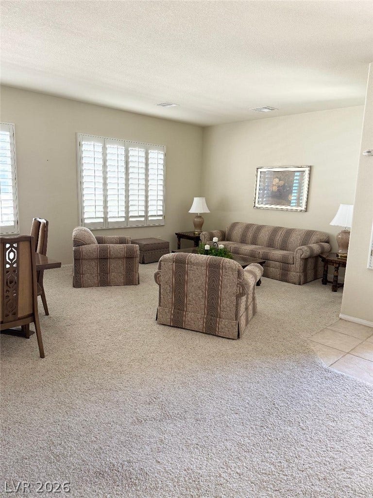 Generous windows with plantation shutters fill this carpeted living area with soft natural light.