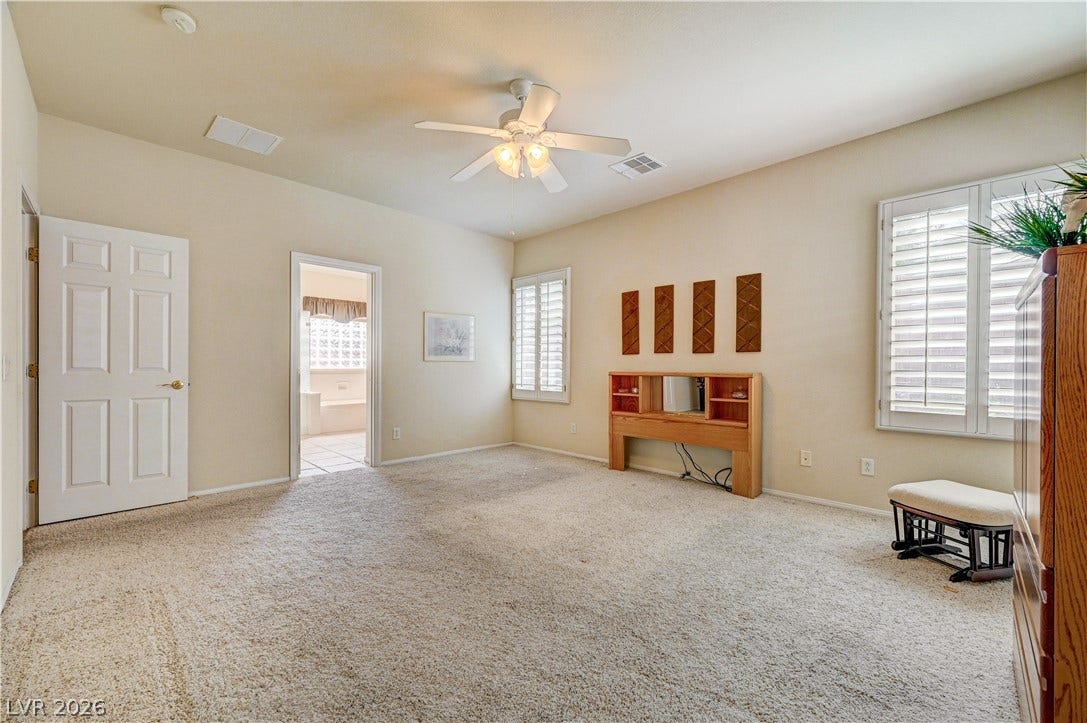 An open bedroom layout features soft wall-to-wall carpeting and classic plantation shutters.