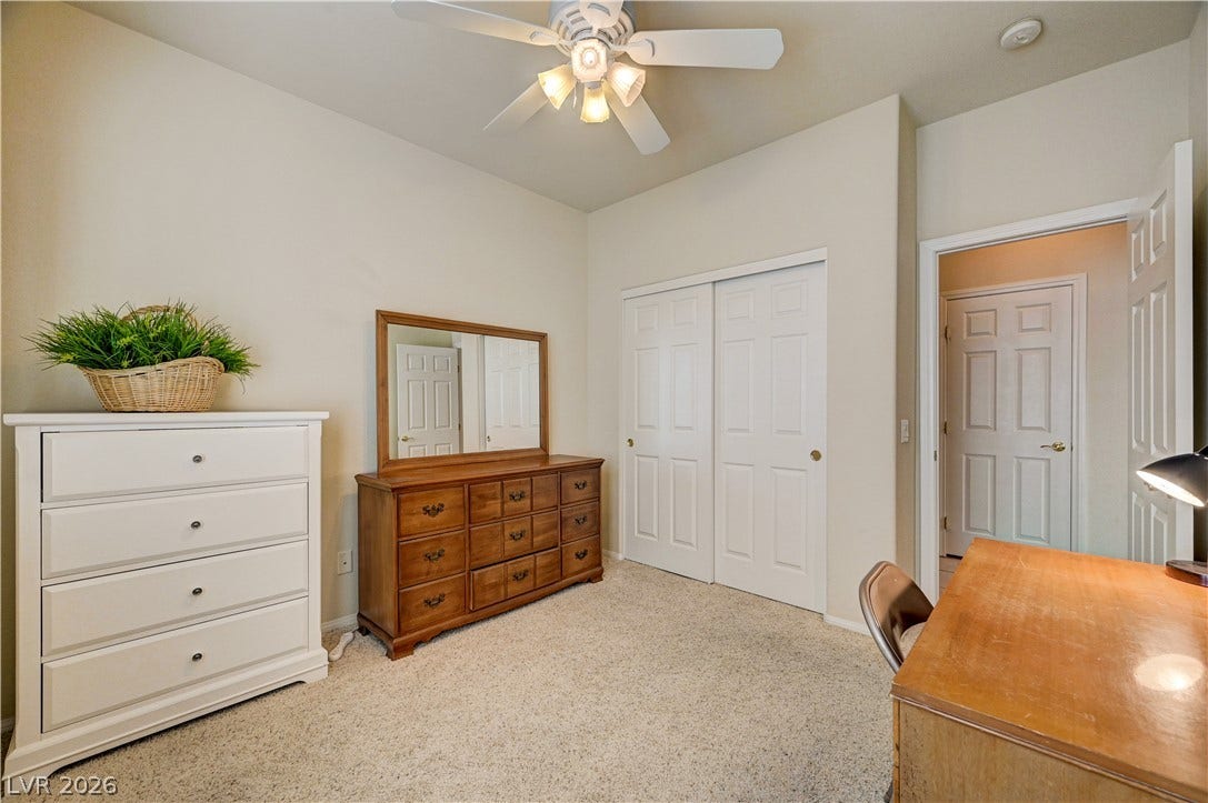 A spacious secondary bedroom features neutral wall tones and soft carpeting throughout.