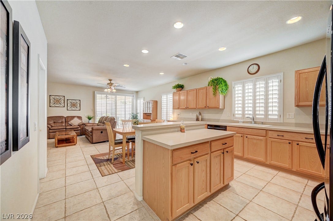 An open layout connects the kitchen, dining, and living spaces over continuous tile flooring.