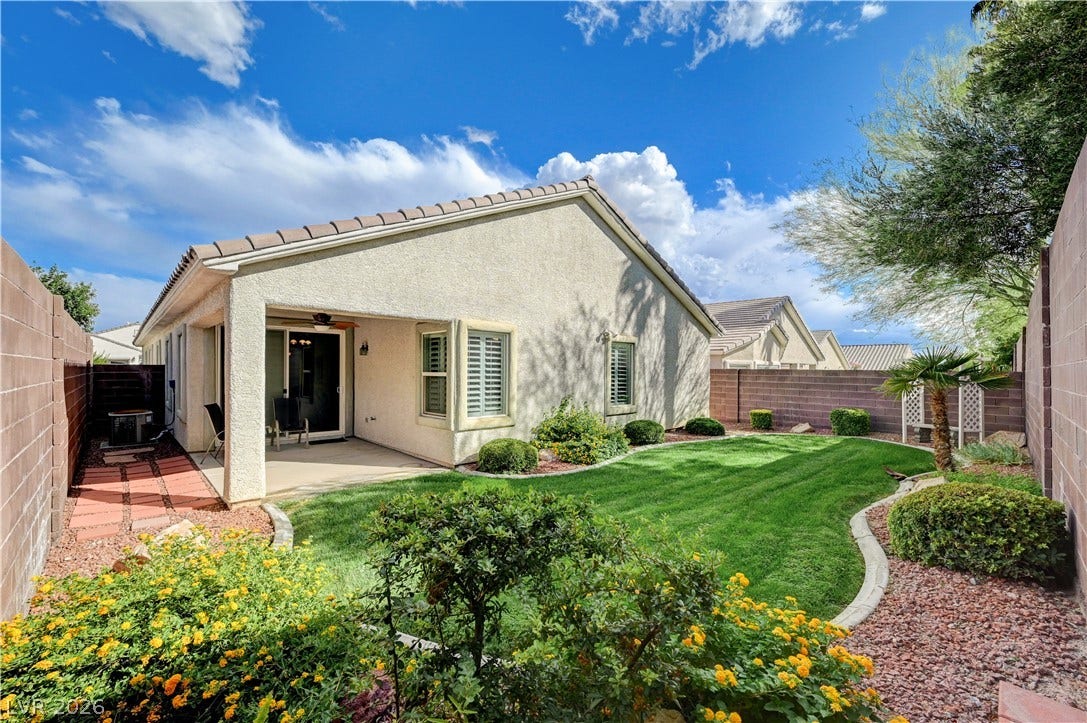 Lush green sod and low-maintenance landscaping create a private backyard retreat under clear blue skies.