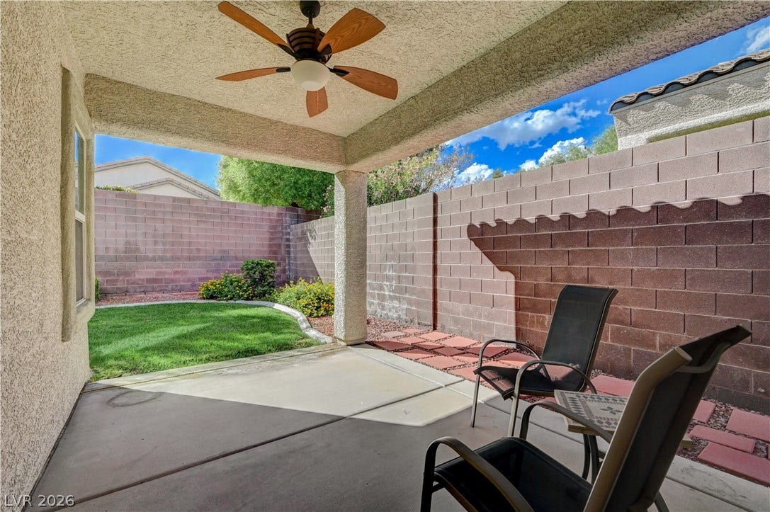A sheltered concrete patio looks out onto a tidy, block-walled yard with green lawn.