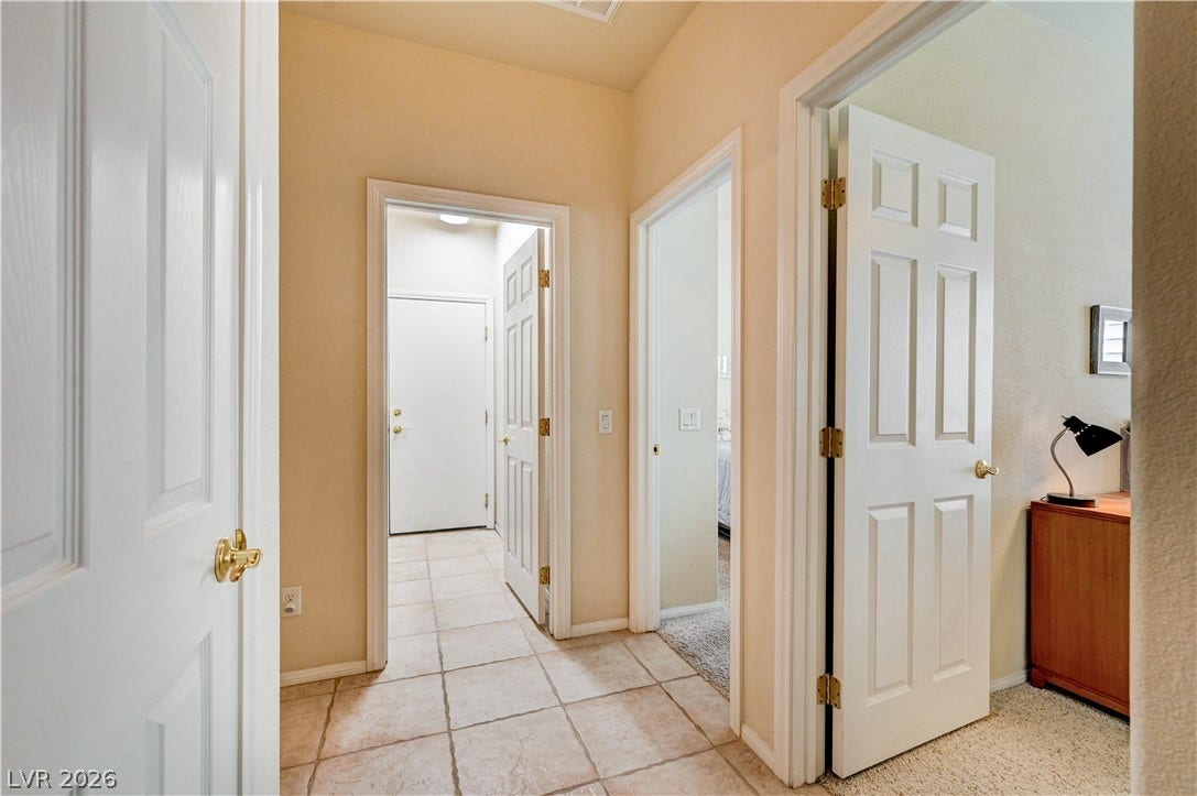 Classic tile flooring and raised panel doors define this functional central corridor.