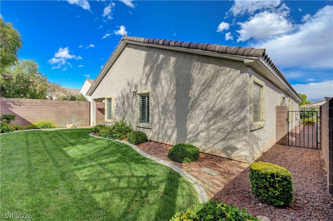 Manicured green lawn and gravel pathways border this stucco exterior under a tile roof.