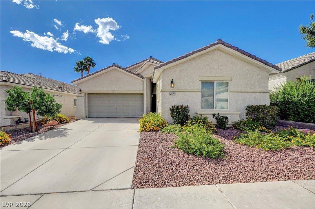 Manicured desert landscaping frames the concrete driveway and stucco exterior of this inviting home.