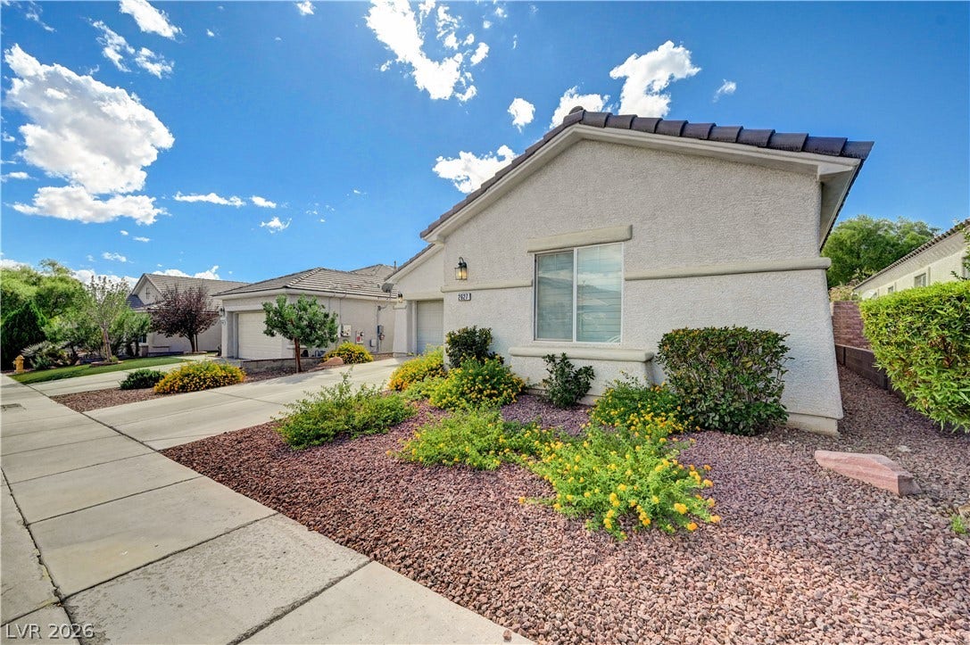 Manicured desert landscaping and paved sidewalks frame this classic stucco exterior under blue skies.