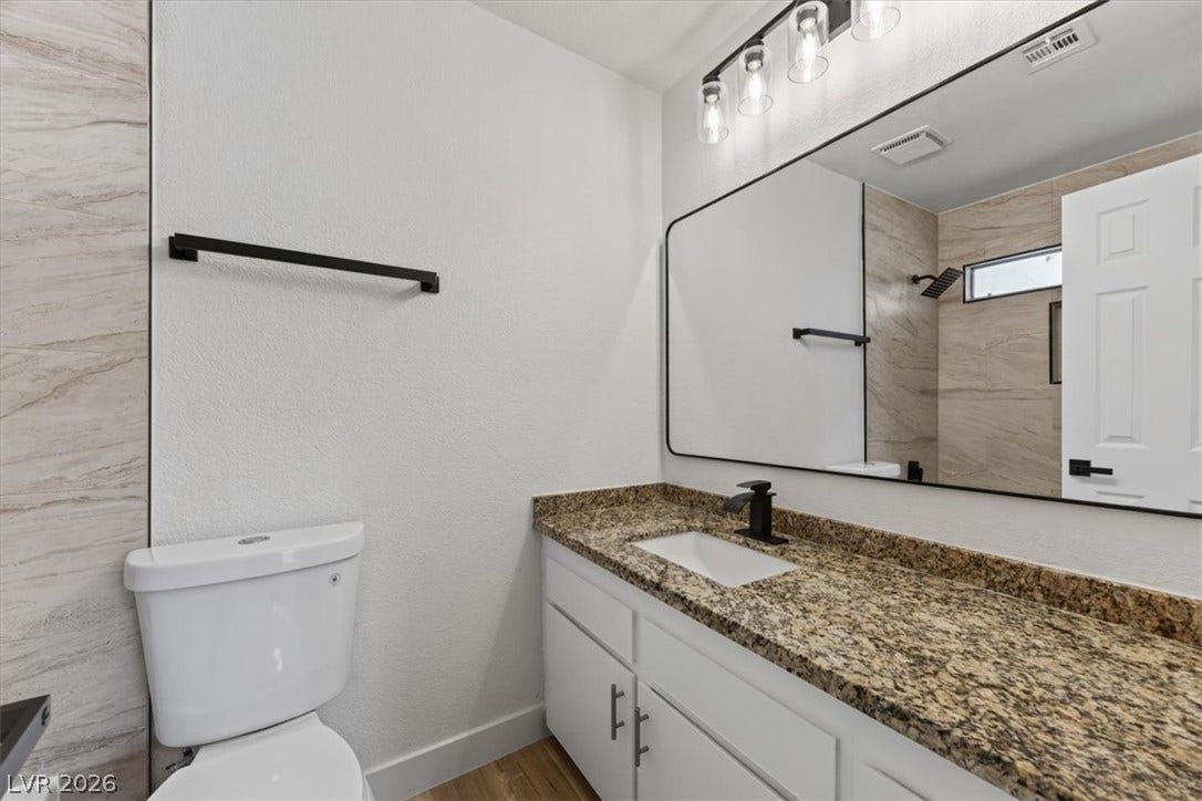 4454 W Desert Inn Road, #D, Las Vegas, NV 89102 Rich granite countertops pair with modern dark hardware in this updated bathroom.