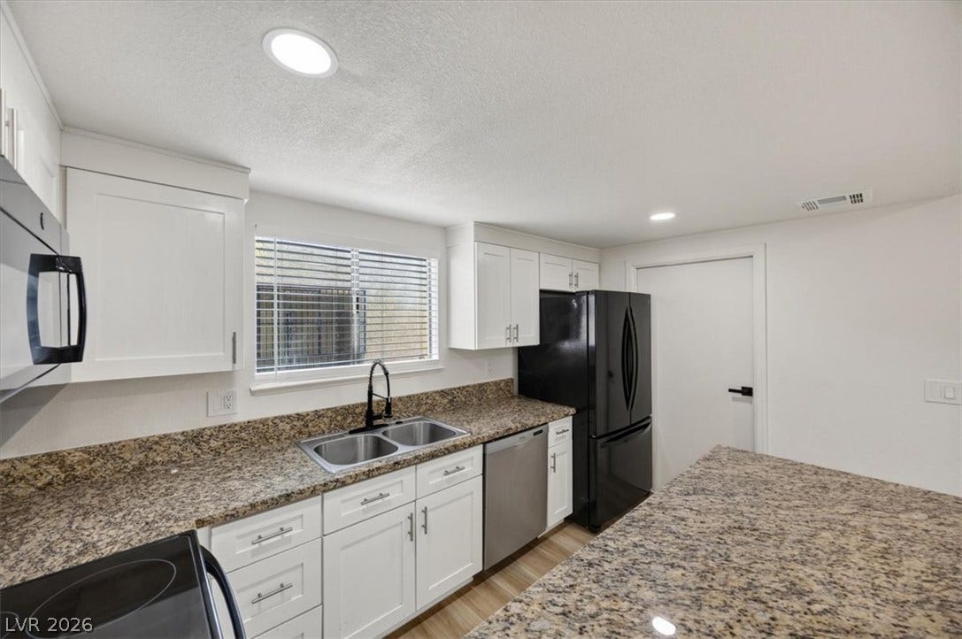 4454 W Desert Inn Road, #D, Las Vegas, NV 89102 Polished granite countertops accent classic white cabinetry in this thoughtfully updated workspace.