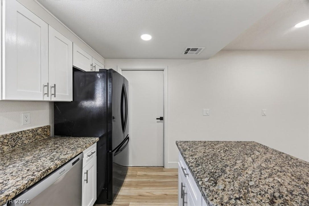 4454 W Desert Inn Road, #D, Las Vegas, NV 89102 Rich granite countertops complement modern cabinetry and wood-look flooring in this updated kitchen.