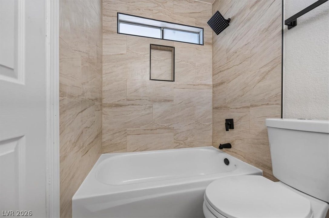 4454 W Desert Inn Road, #D, Las Vegas, NV 89102 Elegantly tiled walls enclose a modern tub and shower combination with sleek dark fixtures.