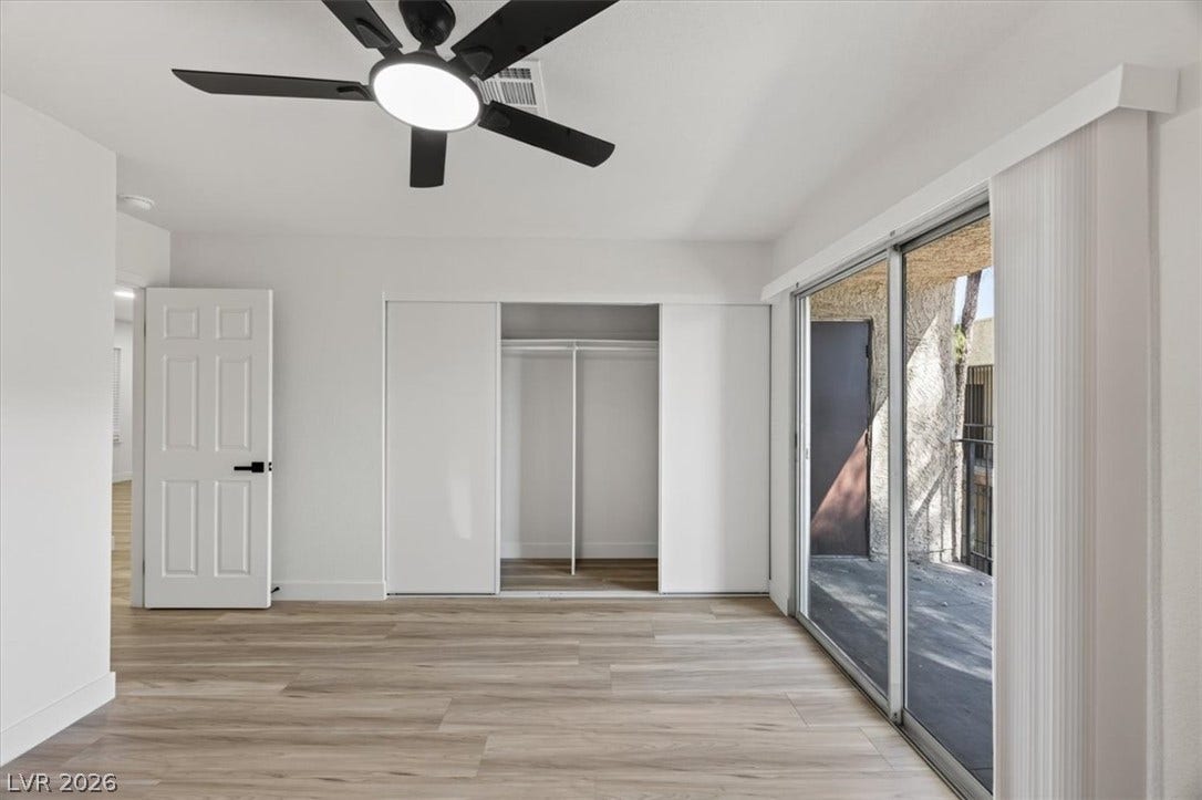 4454 W Desert Inn Road, #D, Las Vegas, NV 89102 Glass sliding doors open to a private balcony from this modern bedroom with wood-look flooring.